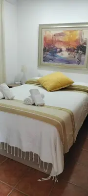 a large white bed with a painting on the wall at Playa Las Redes in El Puerto de Santa María