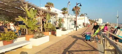 a group of people walking down a sidewalk with plants at Playa Las Redes in El Puerto de Santa María