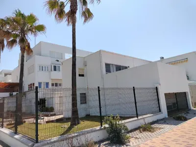 a white building with palm trees in front of it at Playa Las Redes in El Puerto de Santa María