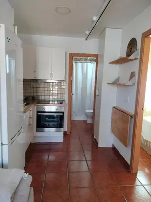 a kitchen with white cabinets and a tile floor at Playa Las Redes in El Puerto de Santa María