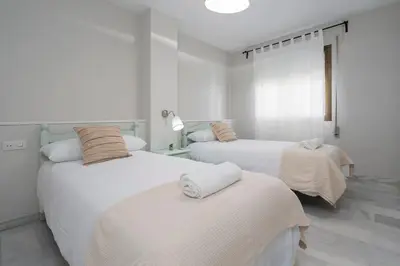 two beds in a room with white walls at Apartoyou - Vistahermosa vistas in El Puerto de Santa María