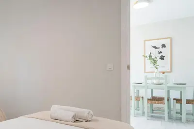 a white bedroom with a bed and a table at Apartoyou - Vistahermosa vistas in El Puerto de Santa María