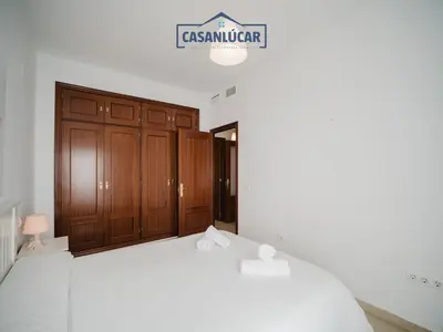a bedroom with a white bed and wooden cabinets at Carmen Viejo primero in Sanlúcar de Barrameda
