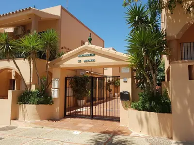 a building with a gate with palm trees in front at Al- Andalus in Novo Sancti Petri