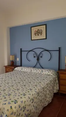 a bedroom with a bed with a blue wall at Al- Andalus in Novo Sancti Petri