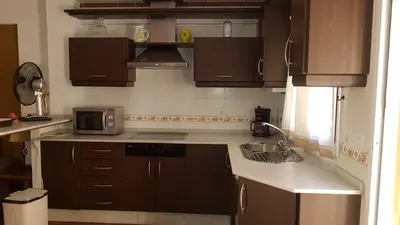 a kitchen with brown cabinets and a sink and a microwave at Al- Andalus in Novo Sancti Petri