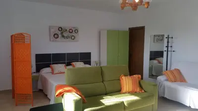a living room with a couch and a bed at LOFT Ajardinado en Roche CONIL in Conil de la Frontera