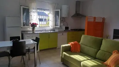 a living room with a green couch and a kitchen at LOFT Ajardinado en Roche CONIL in Conil de la Frontera