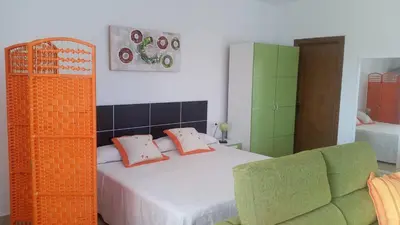 a bedroom with a bed and a green couch at LOFT Ajardinado en Roche CONIL in Conil de la Frontera