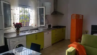 a kitchen with a sink and a window and a table at LOFT Ajardinado en Roche CONIL in Conil de la Frontera