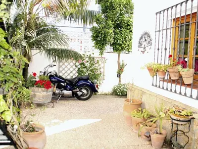 a motorcycle parked in a courtyard with potted plants at Apartamento Caracola Comfortable holiday residence in Chipiona