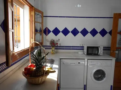 a kitchen with a washing machine and a basket of fruit at Apartamento Caracola Comfortable holiday residence in Chipiona