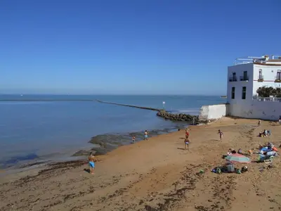 a group of people on a beach near the water at Apartamento Caracola Comfortable holiday residence in Chipiona