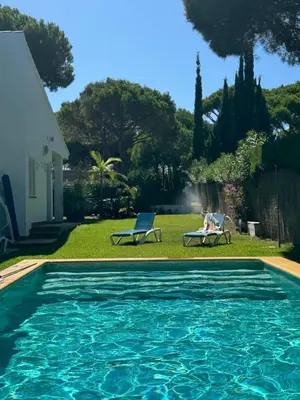 a swimming pool with two chairs and a house at VillaMarte in Conil de la Frontera