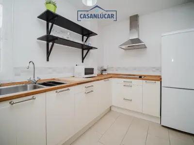 a white kitchen with a sink and a refrigerator at Carmen Viejo bajo in Sanlúcar de Barrameda