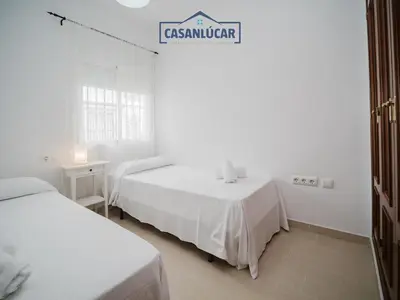 a white room with two beds and a sign at Carmen Viejo bajo in Sanlúcar de Barrameda