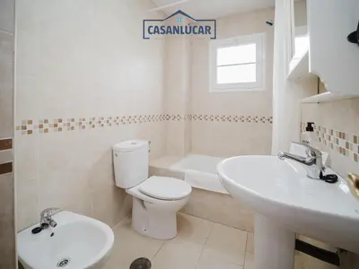a white bathroom with a toilet and a sink at Carmen Viejo bajo in Sanlúcar de Barrameda