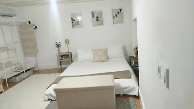 a white bedroom with a bed and a table at GuestReady - La Merced Cadiz in Cádiz