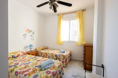a bedroom with two beds and a window at Costa Ballena - Apt para 6 con piscina, terraza, WiFi y parking gratis in Rota