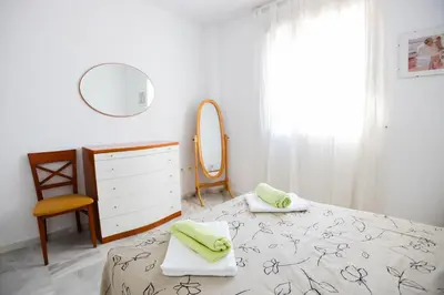 a bedroom with a bed and a dresser and a mirror at Costa Ballena - Apt para 6 con piscina, terraza, WiFi y parking gratis in Rota