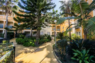 a courtyard with palm trees and a building at Costa Ballena - Apt para 6 con piscina, terraza, WiFi y parking gratis in Rota