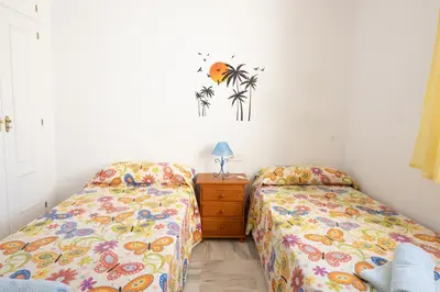 a bedroom with two beds and a dresser with a night stand at Costa Ballena - Apt para 6 con piscina, terraza, WiFi y parking gratis in Rota
