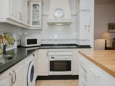 a white kitchen with a stove and a sink at La casa del Ceramista in Sanlúcar de Barrameda