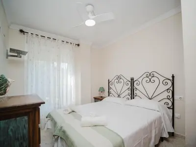 a white bedroom with a bed and a window at La casa del Ceramista in Sanlúcar de Barrameda