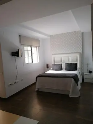 a white bedroom with a large bed and a window at Vivienda en Jerez de la Frontera in Jerez de la Frontera