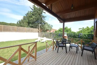 a wooden deck with chairs and a table on it at Villa Farom in Cádiz