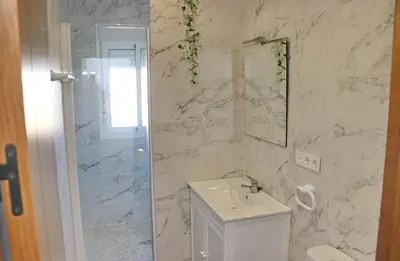 a white bathroom with a sink and a shower at Casa Nispero in Conil de la Frontera