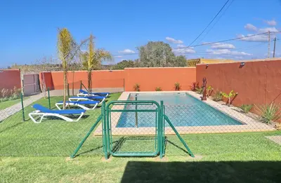 a pool with two chairs and a swing at Casa Nispero in Conil de la Frontera