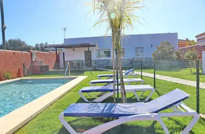 a row of lounge chairs next to a swimming pool at Casa Nispero in Conil de la Frontera