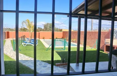 a view through a window of a yard at Casa Nispero in Conil de la Frontera