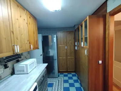 a kitchen with wooden cabinets and a refrigerator at Virgen de los Milagros in El Puerto de Santa María