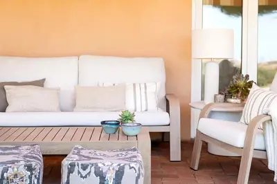 a living room with a white couch and a chair at Apto Lujo Exclusivo vistas Golf y Mar in Novo Sancti Petri