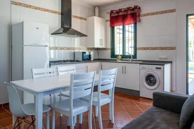 a kitchen with a white table and chairs in a kitchen at Casas Rurales Pericón in Conil de la Frontera