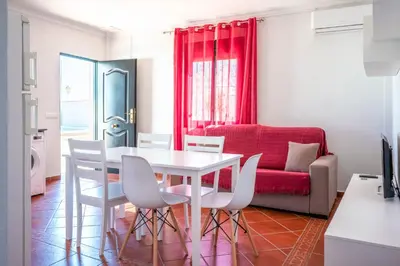 a living room with a table and chairs and a red couch at Casas Rurales Pericón in Conil de la Frontera