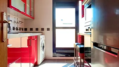 a kitchen with red cabinets and a washing machine at El Ático de la Angelita by RentCadiz in El Puerto de Santa María