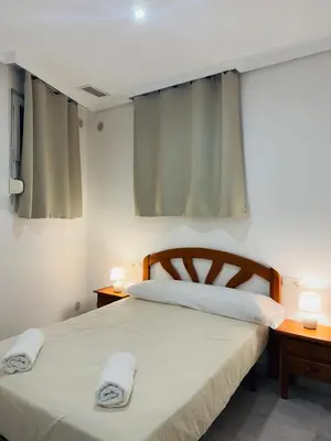 two beds in a bedroom with two lamps and curtains at La Casita Gaditana Centro in Cádiz