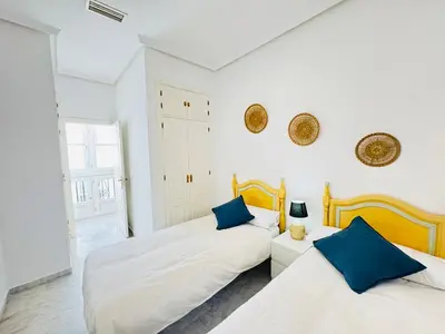 two beds in a white room with blue pillows at La Casita Gaditana in Cádiz