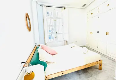 a white bedroom with a bed and a window at La Casita Gaditana in Cádiz