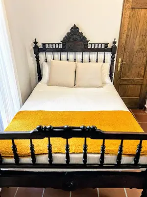 a bedroom with a bed with a black frame and yellow sheets at La Posada de Zepeda in Jerez de la Frontera