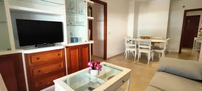 a living room with a television on a dresser with a table at Apartamento Cabo Noval in Sanlúcar de Barrameda