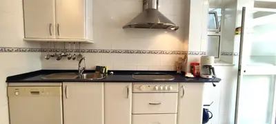 a small kitchen with white cabinets and a sink at Apartamento Cabo Noval in Sanlúcar de Barrameda