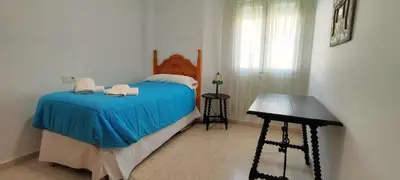 a bedroom with a bed with blue sheets and a desk at Apartamento Cabo Noval in Sanlúcar de Barrameda