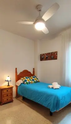 a bedroom with a bed and a ceiling fan at Apartamento Cabo Noval in Sanlúcar de Barrameda