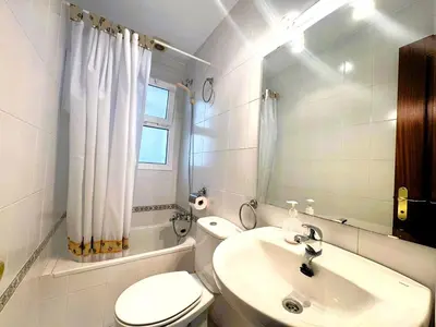 a white bathroom with a toilet and a sink at Apartamento Cabo Noval in Sanlúcar de Barrameda