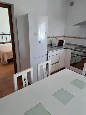 a kitchen with a refrigerator and a table and chairs at Villa Encanto Chiclana in Novo Sancti Petri