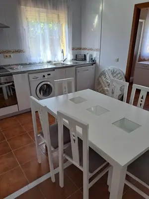 a white kitchen with a white table and chairs at Villa Encanto Chiclana in Novo Sancti Petri